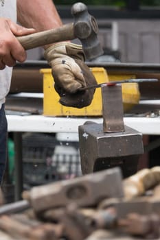 A blacksmith hammering hot iron during medieval fair festival in Streatham Park in London