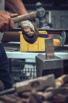 A blacksmith hammering hot iron during medieval fair festival in Streatham Park in London