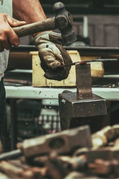 A blacksmith hammering hot iron during medieval fair festival in Streatham Park in London