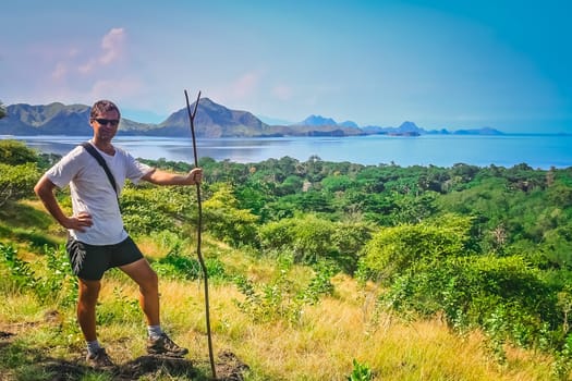 Trekker with a primitive walking stick replacement standing on a hill on the Komodo island, Indonesia