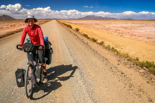 Woman cycling on the remote road in rural part of Bolivia
