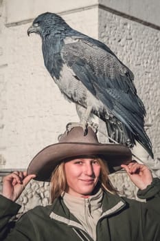 Female tourists with a native to the Andes eagle sitting calmly on her hat in the Colca Canyon in Peru, South America