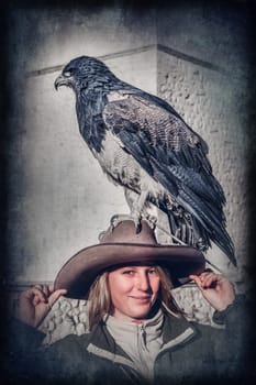 Female tourists with a native to the Andes eagle sitting calmly on her hat in the Colca Canyon in Peru, South America