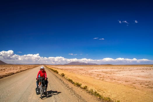 Woman cycling on the remote road in rural part of Bolivia
