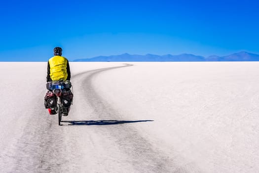 Lonely male cyclist travelling through the biggest salar in the world - Salar de Uyuni in Bolivia