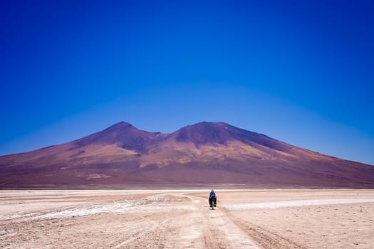 Lonely female cyclist travelling through the biggest salar in the world - Salar de Uyuni in Bolivia