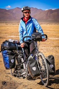 Female cyclist stuck in deep sand in the dry, desolate, empty rural countryside in central Bolivia