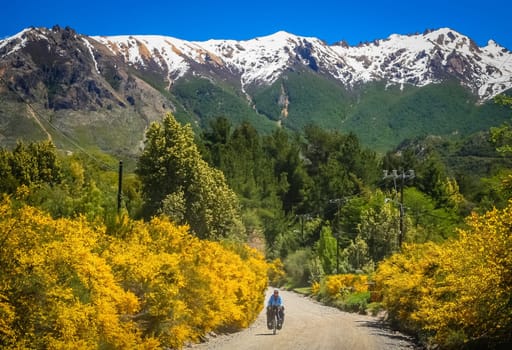 Woman cycling on the corrugated road through the mountains in Lake District, Argentina