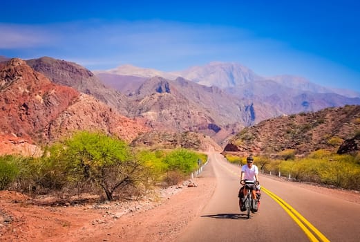 Man cycling on the empty road to Cafayate in the remote part of north west Argentina