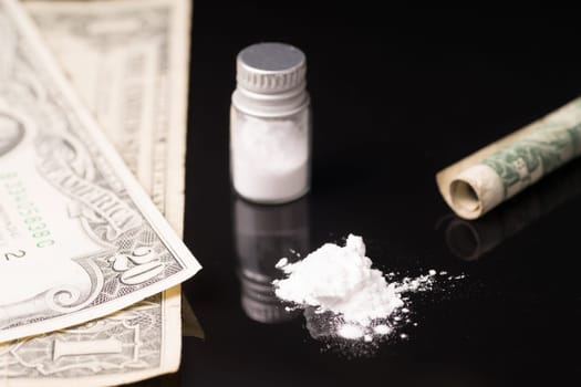 cocaine or other illegal drugs that are sniffed by means of a tube, isolated on black glossy background