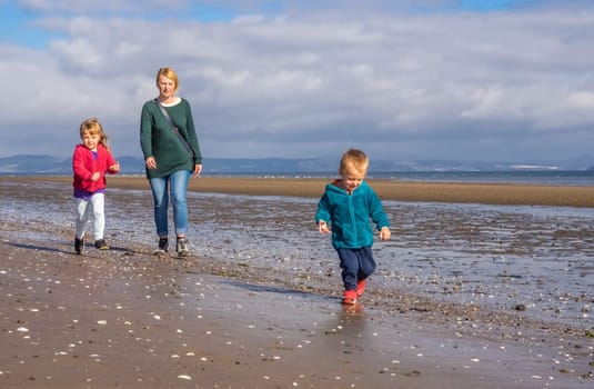 Mom with kids walking on a beach in Portobello in Edinburgh