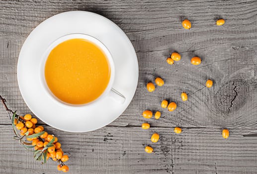 Sea buckthorn juice on a wooden table. A branch of sea-buckthorn and berries top view.