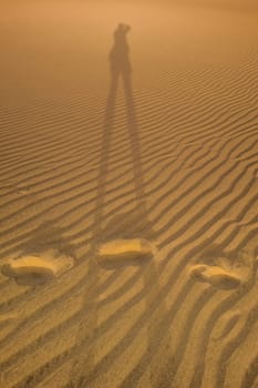 Shadow of a photographer taking picture of the sand dunes in the Natural Reserve of Dunes of Maspaloma in Gran Canaria