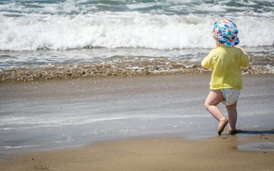 Little boy running towards the sea on holiday
