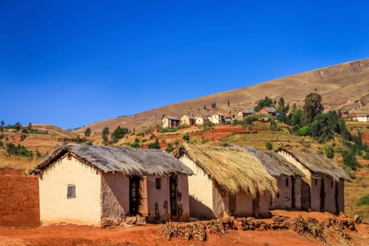 Row of four primitive huts in central plateau in Madagascar