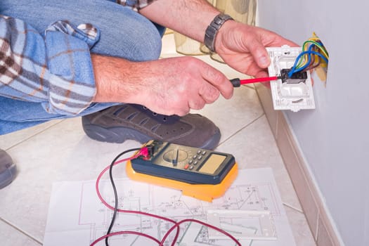 Electrician's hands assembles a standard bipolar wall socket.