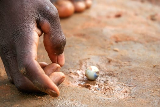 Small Malagasy boy playing with tiny balls