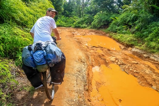 Cyclist struggling with bicycle on difficult jungle track towards Mananara on the Vanilla Coast in Madagascar