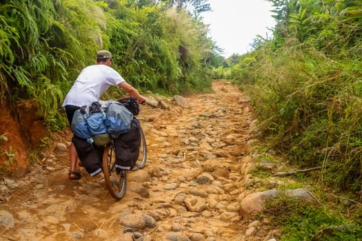 Cyclist struggling with bicycle on difficult jungle track towards Mananara on the Vanilla Coast in Madagascar