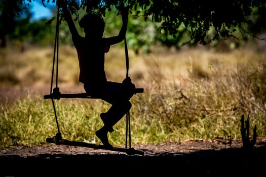 Silhouette of a Malagasy girl having fun on a swing, Madagascar