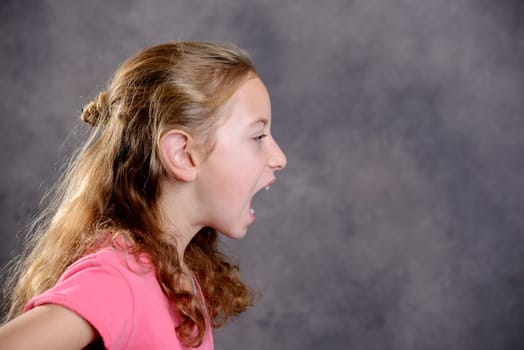 angry girl with blond hair and pink shirt in front of gray background