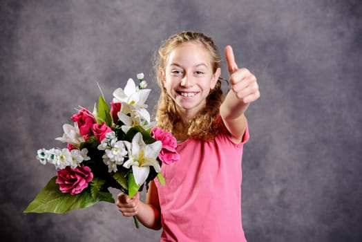 nice blond girl bouquet of flowers and thumb up in front of gray background