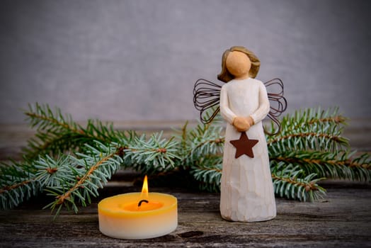 christmas sill with angel,fir branch and candle on wooden ground