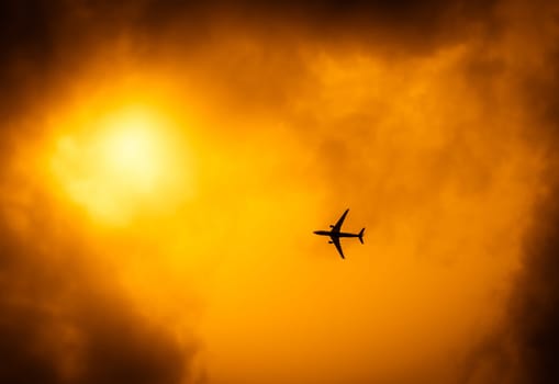 Commercial passenger plane flying over the dramatic golden evening sky