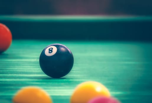 Black billard ball number eight on green billard table