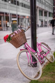 Red and pink bicycle with a basket attached on the street in London centre