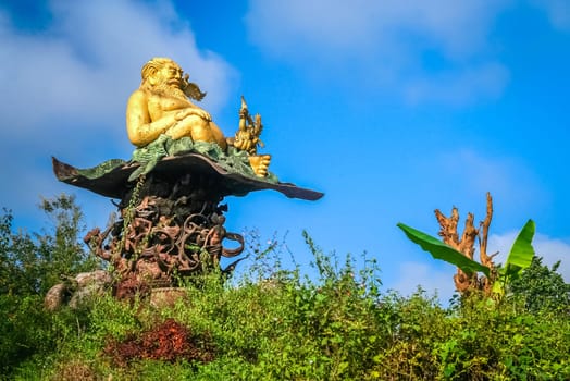 Golden figure of a fat man in an abandoned temple complex in Xishuabanna region of Yunnan, southern China