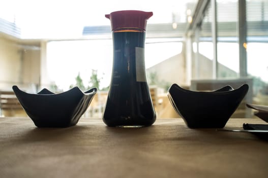 Japanese tablewares. Soya sauce bottle and two bowl over table. Closeup