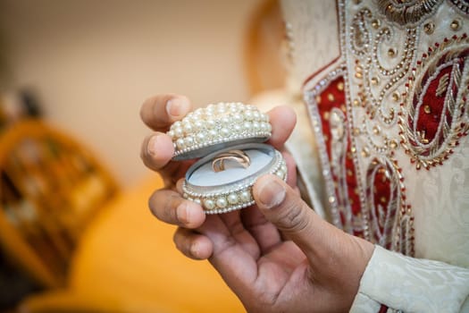 Indian groom showing open box containing wedding rings