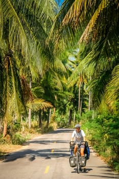 Female cyclist cycling through tropics in central Thailand