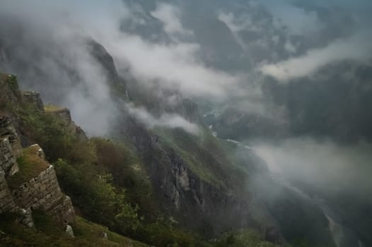 Ancient inca town of Machu Picchu covered in mist, fog and clouds in the morning, Peru