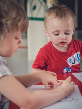 Little kids colouring pictures during art time at the nursery