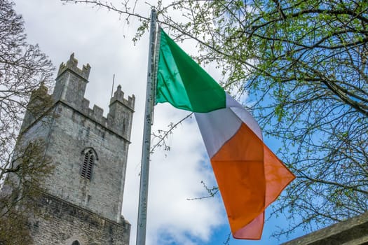 Irish flag fluttering in front of the tower of an Old St Mary Cathedral, Limerick, Ireland