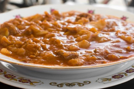 Stew with cabbage, goulash in plate with flower pattern.