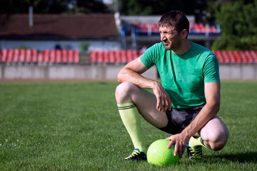 Football player or soccer player with ball on green sports field.