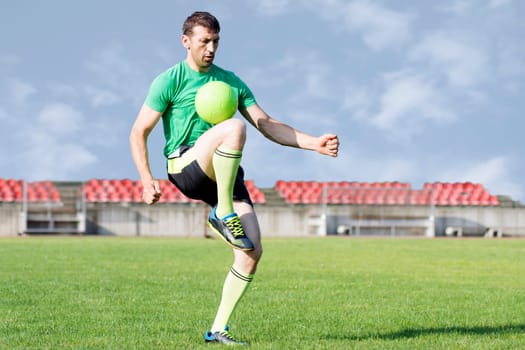 The soccer player is playing with ball in the stadium.