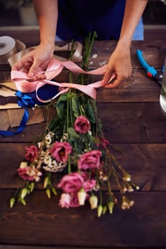 Florist decorating rose bouquet with ribbon