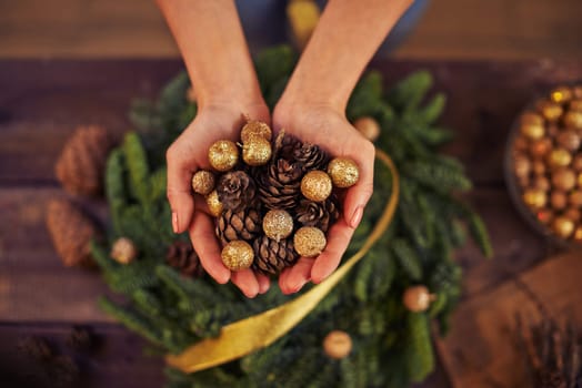 Close-up of female hands with fir-cones and golden balls