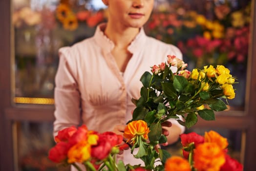 Woman at flower shop holding bunch of flowers