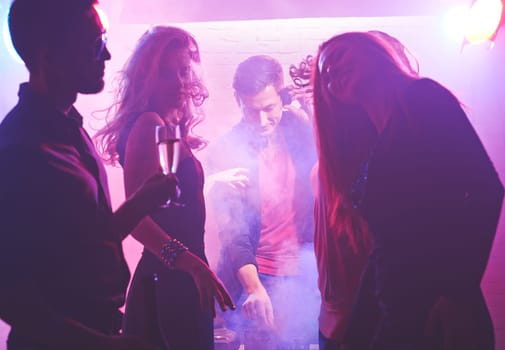 Deejay working and cool girls dancing in nightclub