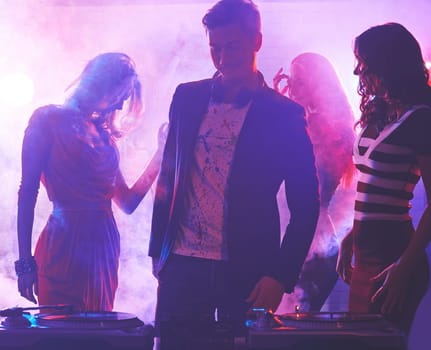 Group of girlfriends dancing in nightclub with dj near by