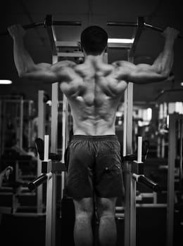 Young man training on special sport equipment in gym