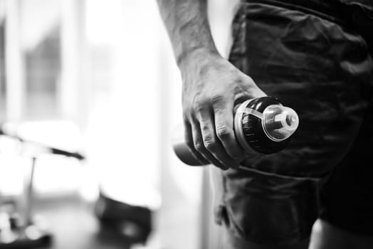 Hand of young man holding bottle with water in gym