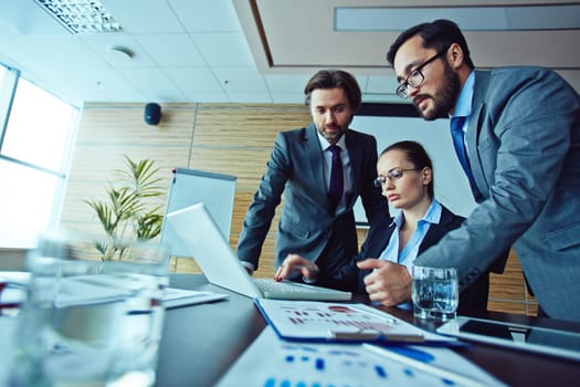 Team of three workers looking at laptop screen