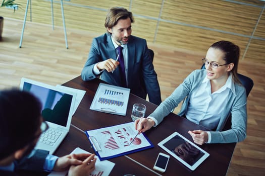 Three business people discussing financial report of one worker