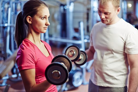 Portrait of pretty girl training with barbells in gym